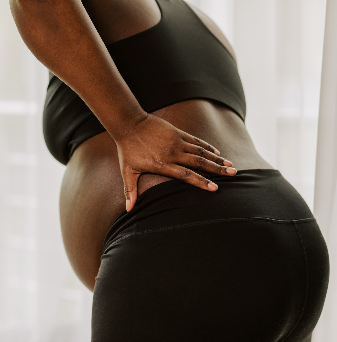 A pregnant woman seeks relief from lower back discomfort, a common issue during pregnancy. Chiropractic care can provide gentle and tailored support for expectant mothers.
